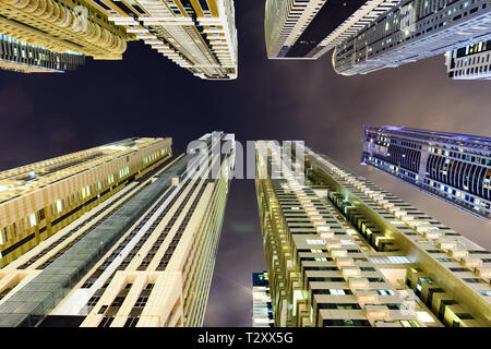 (Prospettiva diversa) Splendida vista dal basso verso l'alto di alcuni alti grattacieli e torri accesa durante la notte in Marina di Dubai. Foto Stock