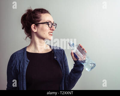 Caucasian donna sorridente con una bottiglia di acqua Foto Stock