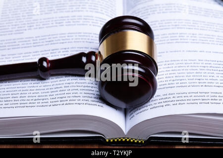 Close-up di martello di legno e aprire il libro di diritto Foto Stock