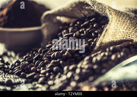 I chicchi di caffè nel sacco di tela sul vecchio tavolo in legno. Foto Stock
