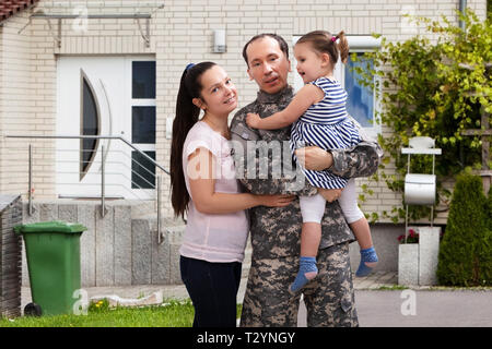 Close-up di un soldato felice riunita con la famiglia al di fuori della loro casa Foto Stock