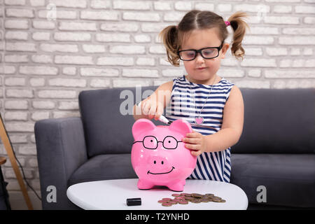 Felice ragazza carina dipinto su Salvadanaio con pennarello nero a casa Foto Stock