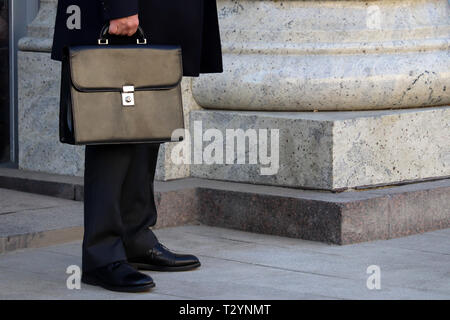 Uomo in un business suit con una cartella in pelle in piedi all'aperto. Nozione di imprenditore, gazzetta, politico, carriera Foto Stock