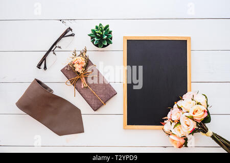 Piano immagine di laici di scatola regalo, cravatta, bicchieri, fiori di rose e uno spazio vuoto lavagna. Vista da sopra con copia spazio per la vostra pubblicità di testo. Felice Fathe Foto Stock