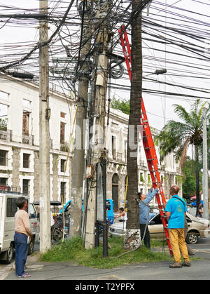 Manila, Filippine: un gruppo di uomini che fissa i cavi su un post con l aiuto di una scala nella storica città di Intramuros Foto Stock