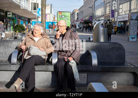 Coppia di anziani seduti su una panchina di cemento sulla landa zona pedonale a Sheffield Foto Stock