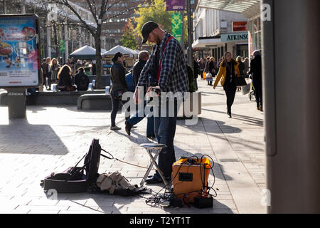 Busker con la chitarra acustica e amplificatore palying sul Moor strada pedonale per lo shopping precinct su una giornata invernale e in Sheffield Foto Stock