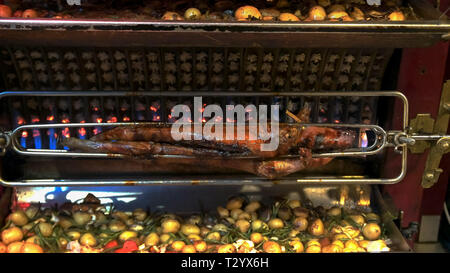 Un maialino, polli e verdura essendo arrostito su una rosticceria a un ristorante a Parigi Foto Stock