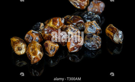 Mazzetto di secco kurma date o palm isolato in nero con la riflessione al di sotto di esso Foto Stock