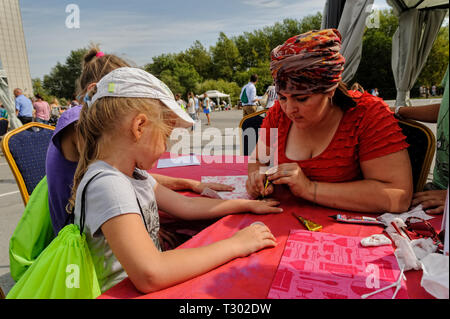 Tyumen, Russia - Agosto 26, 2016: Open Day di Sberbank per bambini. Artista applicando henna tattoo sulla mano ragazza Foto Stock