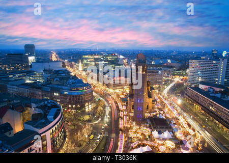 Vista in elevazione del Kaiser Wilhelm Memorial Church e i Mercatini di Natale al tramonto, Foto Stock