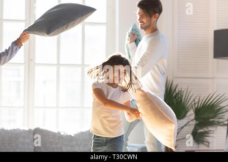 Famiglia allegra e piccola figlia gioca con cuscini a casa Foto Stock