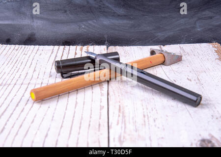 Vecchio legno bianco di fronte a una lavagna con penna stilografica e matita di legno in sharpener Foto Stock