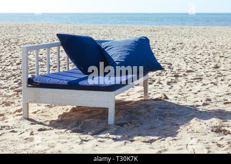 Bellissima spiaggia con due cuscini blu sulla chaise longue. Il mare e la montagne di sabbia sono illuminate dal sole del mattino. Foto Stock