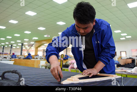 (190405) -- DONGXIANG, 5 aprile 2019 (Xinhua) -- un lavoratore taglia tessuto per ombrelli a un workshop in Dongxiang contea autonoma, a nord-ovest della Cina di Provincia di Gansu, 3 aprile 2019. Dal 2018, la lotta contro la povertà i workshop hanno dato la priorità ad accelerare la povertà continua campagna di aiuti in Dongxiang contea autonoma, da cui poveri hanno guadagnato un costante lavoro per contribuire a sollevare il loro stato di povertà. Finora, 18 alleviamento della povertà workshop sono stati stabiliti, la creazione di opportunità di lavoro per oltre 700 locali, compresi più di 500 registrati persone povere. Per capit Foto Stock