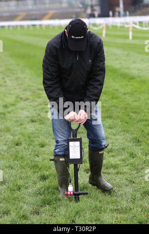 Ritratto di Ground Steward utilizzando penetrometro a Aintree, Liverpool, aprile 2019. Going 'Good to Soft' Soil Impact GoingStick Tester al Grand National Racecourse. Meteo Regno Unito. Forti venti e docce pesanti per il 2 ° giorno del festival di equitazione. Foto Stock