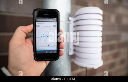 Amburgo, Germania. 05 apr, 2019. In occasione di una conferenza stampa su un balcone in HafenCity, un uomo possiede uno smartphone accanto a un dispositivo di misurazione che raccoglie i dati sulla qualità dell'aria. Vari punti di misura lungo l'Elba sono registrati sullo smartphone. Con un totale di otto strumenti di misurazione, Nabu (Naturschutzbund Deutschland) vuole monitorare e registrare la qualità dell'aria in prossimità della porta. Credito: Daniel Reinhardt/dpa/Alamy Live News Foto Stock