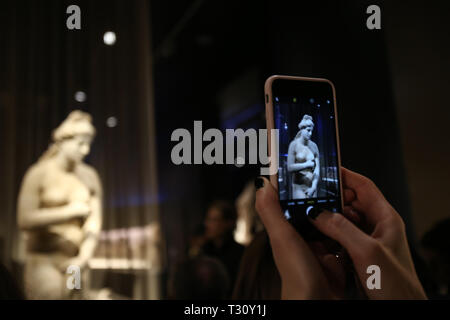 (190405) -- ATENE, 5 aprile 2019 (Xinhua) -- Un visitatore prende le foto di una statua romana della dea greca Afrodite, che viene visualizzata per la prima volta alla fiera "innumerevoli aspetti di bellezza' detenuto dal Museo Archeologico Nazionale di Atene, Grecia, 4 aprile 2019. Una statua in marmo della greca antica dea Afrodite lungo con due profumi dall antichità sono state svelata al Museo Archeologico Nazionale della Grecia il giovedì per contrassegnare un anno di anniversario della Mostra temporanea 'innumerevoli aspetti della bellezza.' per andare con 'Funzione: Afrodite statua on maiden display, Foto Stock