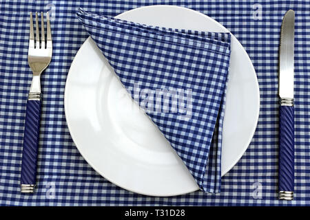 Blu e bianco Tavolo picnic o posizionare l'impostazione. Piastra e coltello e forchetta e Tovagliolo su un Blu Tabella Gingham panno. Foto Stock