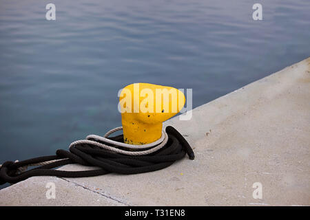 Bollard giallo sul bordo della marina con la fune. Immagine di stock Foto Stock