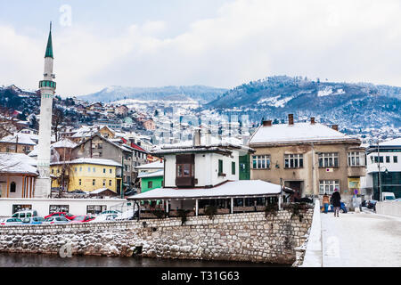 Un minareto sorge su edifici attraverso il fiume dalla città vecchia di Sarajevo, Bosnia Erzegovina Foto Stock