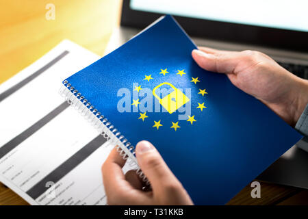 Concetto del GDPR (General Data Protection Regulation). Uomo d'affari che tiene un notebook con il logo della bandiera dell'Unione europea (UE) e l'icona del lucchetto. Foto Stock