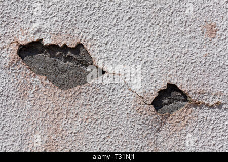 Parete con la vecchia vernice e peeling, dove si può vedere il cemento attraverso due fori aperti nello strato di vernice. Può essere utilizzato come sfondo. Foto Stock