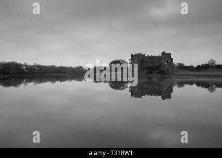 Carew Castle riflettendo in acqua in una nebbiosa mattina, Pembrokeshire Foto Stock