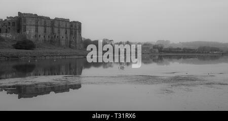 Carew Castle & Mill riflettendo in acqua in una nebbiosa mattina, Pembrokeshire Foto Stock