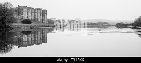 Carew Castle & Mill riflettendo in acqua in una nebbiosa mattina, Pembrokeshire Foto Stock