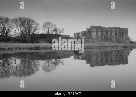 Carew Castle riflettendo in acqua in una nebbiosa mattina, Pembrokeshire Foto Stock