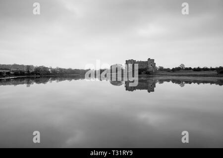 Carew Castle riflettendo in acqua in una nebbiosa mattina, Pembrokeshire Foto Stock