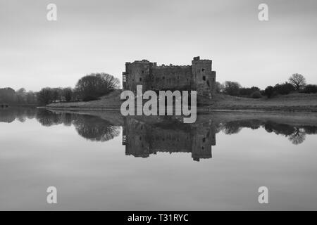 Carew Castle riflettendo in acqua in una nebbiosa mattina, Pembrokeshire Foto Stock