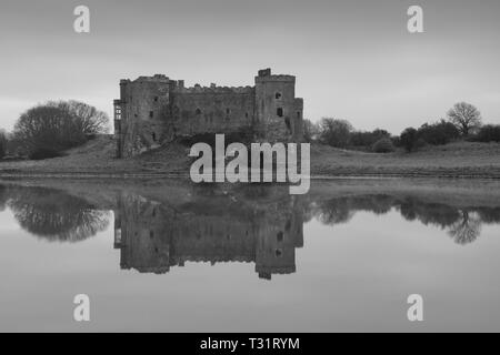 Carew Castle riflettendo in acqua in una nebbiosa mattina, Pembrokeshire Foto Stock