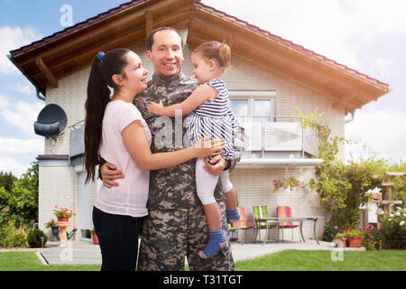 Close-up di un soldato felice riunita con la famiglia al di fuori della loro casa Foto Stock