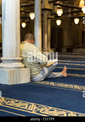 Un musulmano di recitare il libro sacro Corano in una moschea Foto Stock