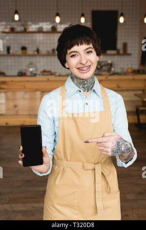 Allegro cameriera puntando con il dito in corrispondenza di smartphone con schermo vuoto Foto Stock