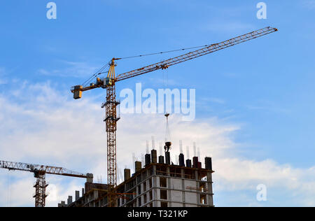 Industrial Gru edili e sagome dei lavoratori durante l'installazione del cassero e strutture in calcestruzzo Foto Stock