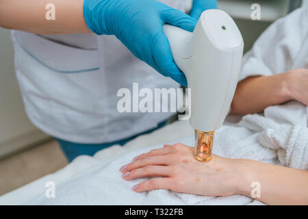 Vista ritagliata della cosmetologo nei guanti di gomma facendo il trattamento con laser Foto Stock