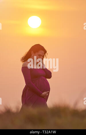 Donna incinta sul soleggiato supporto luce sul cielo chiaro sfondo Foto Stock