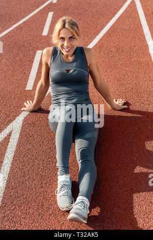 Donna giovane atleta di stadium stile di vita sportiva seduti sulla via Pendente ritornare alla ricerca fotocamera a sorridere allegro Foto Stock
