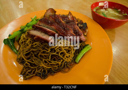 Vista ravvicinata della wantan mee servito con salsa di soia,l'arrosto di maiale e verdure. Si tratta di una cucina Cantonese la cucina cinese. Foto Stock