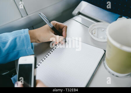 Le donne a lavorare mentre in sella a un treno. Le donne le mani la scrittura in un notebook Foto Stock