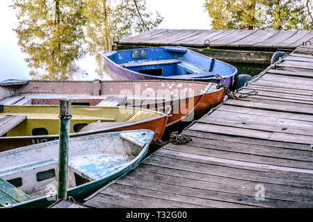 Ferro vecchio sfilacciata e malandata barca legato al dock in legno close-up Foto Stock