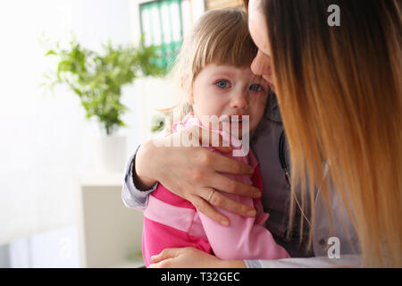 Medico abbracciando la paura di piangere little Baby girl visitando il suo ufficio Foto Stock