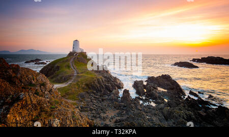 Tramonto spettacolare, faro di Twr Mawr Llanddwyn Island, Anglesey che si affaccia verso l'ingresso meridionale dello stretto di Menai. Fotografia classica del paesaggio britannico. Foto Stock