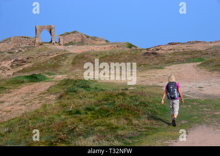 La donna gli escursionisti a piedi su sentiero costiero ai ruderi del castello di Gronez sull'isola di Jersey, nelle Isole del Canale, UK. Foto Stock