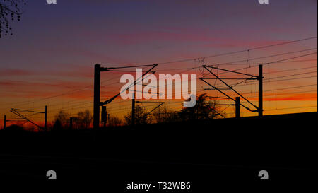 Bahngleise, Oberleitungen, Silhouette mit Bäumen, im Sonnenuntergang Foto Stock