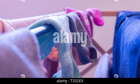 Calze ineguagliabili essiccazione su un rack, diurno. Raffigurante il giorno di Lavanderia, Pulizia casa e manca il calzino coppie. Foto Stock