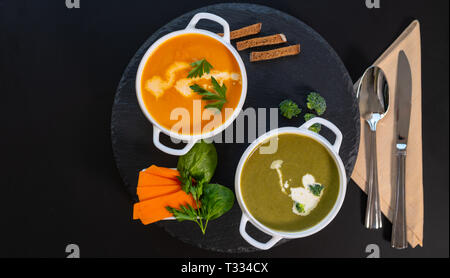 Bocce di sani e zucca butternut zuppe fatte dalla fattoria la verdura fresca farcita con crema e erbe su un round scheda nero visto dal overhea Foto Stock